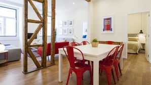 A modern dining area with a white table and red chairs, wooden beams, and a red sofa in the background. - Central Downtown 3D up to 17guests by Central Hill (Lisboa ciudad)