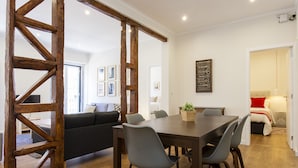 Un comedor con una mesa y sillas de madera, un sofá negro y una estructura de vigas de madera.