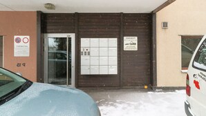 Ein Gebäudeeingang mit Glastür, einem Verbotsschild für Parkplätze und mehreren Briefkästen.