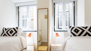 Ein Hotelzimmer mit zwei Betten, einem Spiegel, einem kleinen Tisch und einer Lampe.