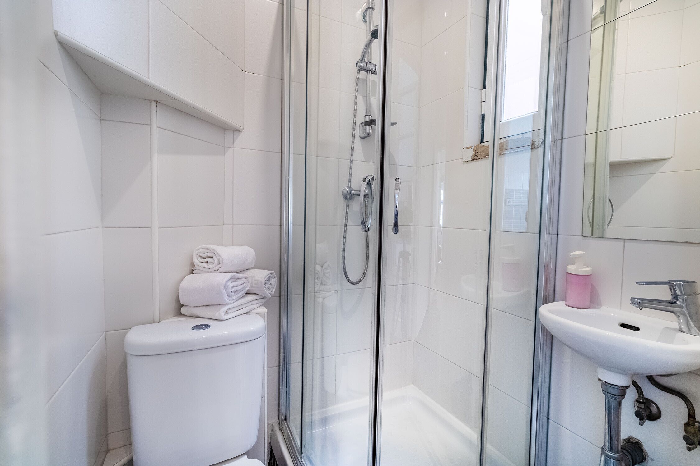 A modern bathroom with a glass-enclosed shower, a white toilet, and a sink with a mirror.