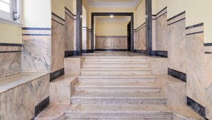 A marble staircase with a handrail, leading to a landing with a door. - Central Chiado RC by Central Hill (Lisboa ciudad)