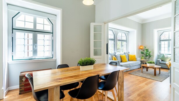 A spacious living area with a wooden dining table and chairs, a sofa with cushions, and a small coffee table. - Central Chiado RC by Central Hill (Lisboa ciudad)