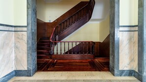 A marble staircase with a wooden handrail and a dark wooden floor.