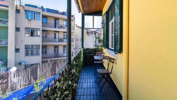 A balcony with a wooden floor, a table, and a chair.