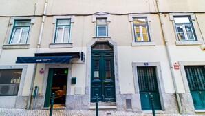 A building with a green door, a visible entrance, and a sign for 'Aruki Sushi Delivery'.
