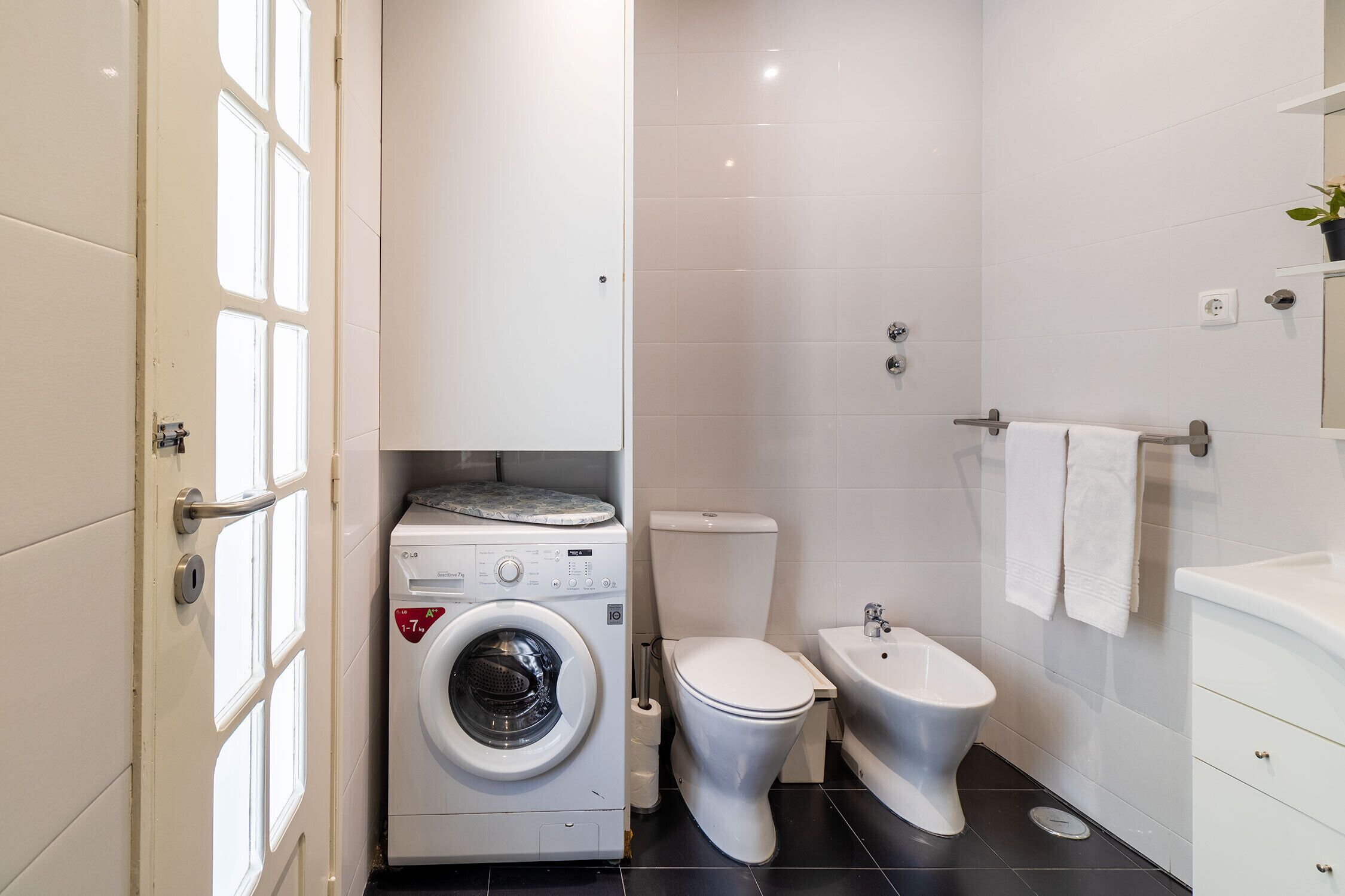 Un baño pequeño con lavadora, inodoro y bañera.