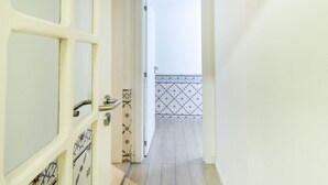 A narrow hallway with a door leading to a balcony with patterned tiles.