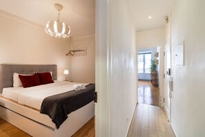 Ein Schlafzimmer mit Bett, Nachttisch, Lampe und einer Pendelleuchte.