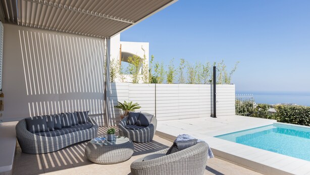 Un espacio al aire libre moderno con piscina, mobiliario y vista al mar.