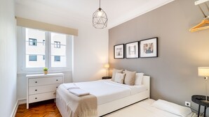 A modern bedroom with a bed, bedside tables, a window, and a hanging light fixture.