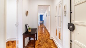 A hallway with wooden flooring, white walls, and a black telephone on the right.