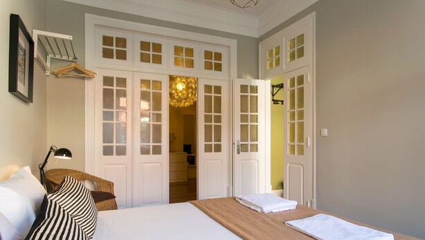 A hotel room with a large bed, a hanging chair, a desk with a lamp, and a wardrobe with multiple doors.