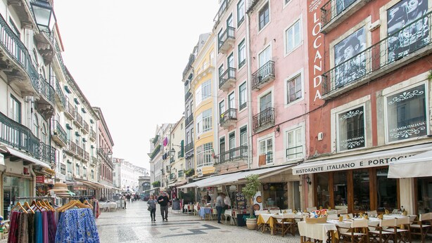 Eine Straße mit Gebäuden, Geschäften und Außenbereichsgastronomie.
