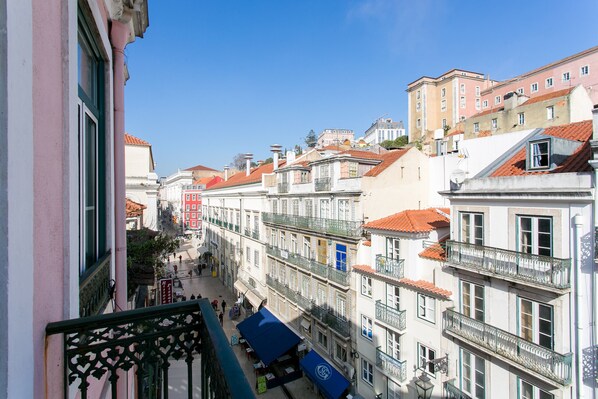 Una calle estrecha flanqueada por edificios, balcones y un cielo azul despejado.