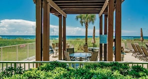 Enjoy ocean views from this pergola, surrounded by palm trees and a white fence, with a table and chairs for a relaxing space.