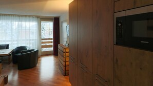 Una cocina moderna con armarios de madera, microondas integrado y un comedor con mesa y sillas.