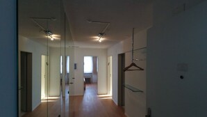 Un pasillo con suelo de madera, un espejo a la izquierda y una puerta al final.