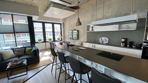 Uma cozinha moderna com uma ilha grande, banquetas e um espaço de jantar com um sofá.