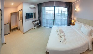 Une chambre d’hôtel avec un grand lit, un bureau, une chaise, une télévision et une fenêtre avec des rideaux.