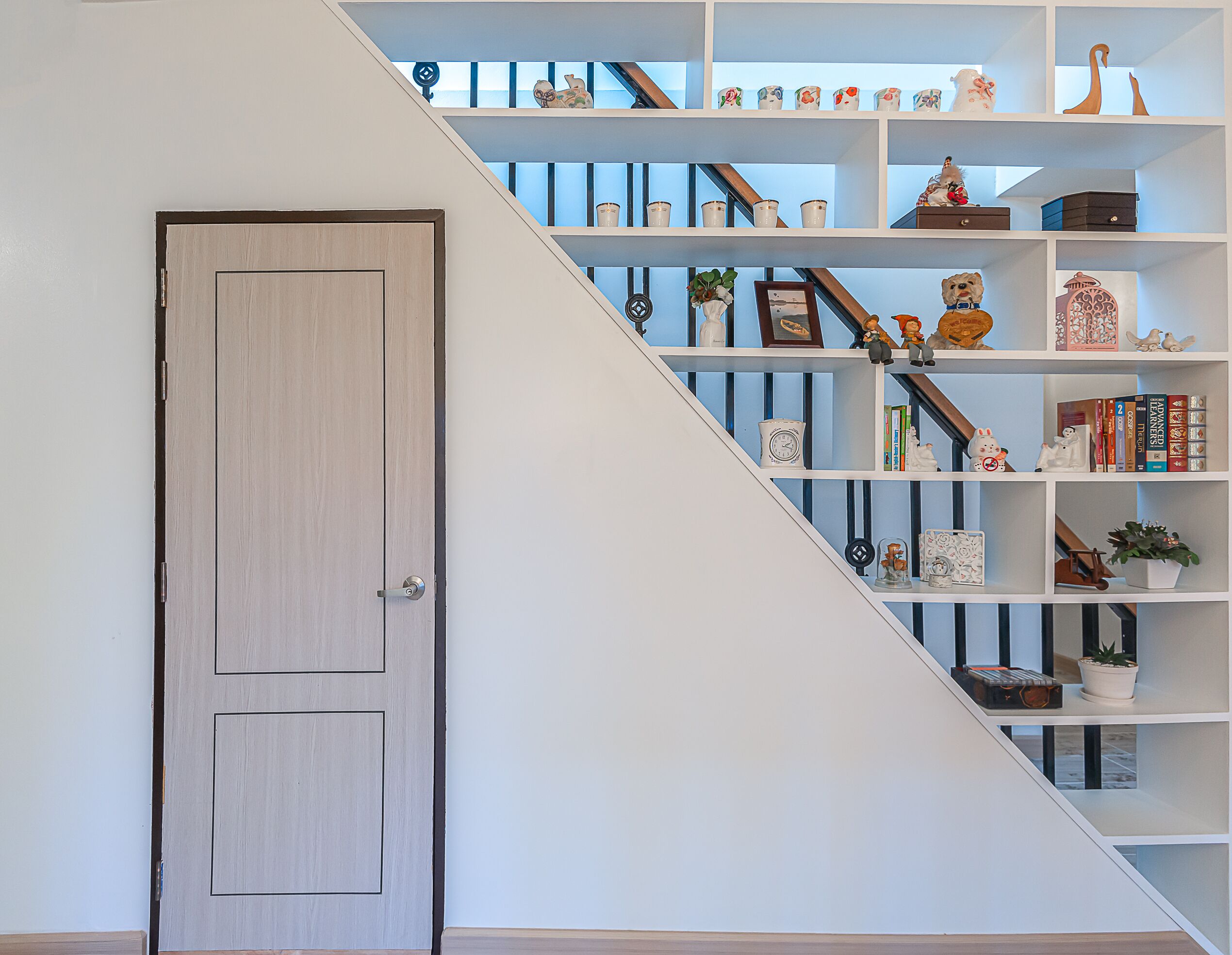 A staircase with white shelves containing various decorative items and books.