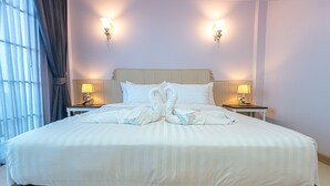 A hotel room with a large bed, two bedside lamps, and a decorative towel arrangement on the bed. - The Great Winter (Chiang Rai)