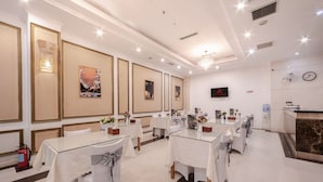 Een restaurant in een hotel met meerdere tafels, stoelen en kunst aan de muren.