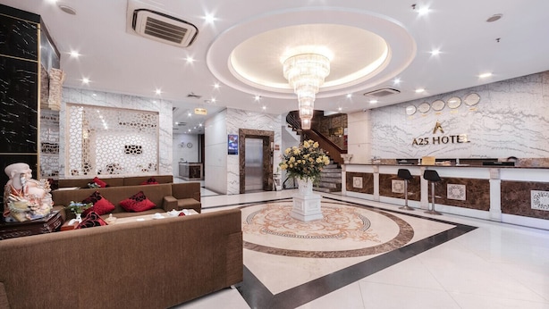 Een hotel lobby met een receptiebalie, een kroonluchter, een ontvangstgedeelte en een trap.