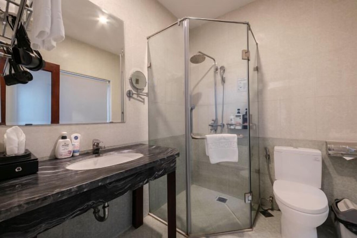 Un bagno moderno con cabina doccia in vetro, un WC bianco e un lavabo in marmo.