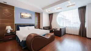 Een hotelkamer met een groot bed, een bureau, een stoel en een raam met gordijnen.