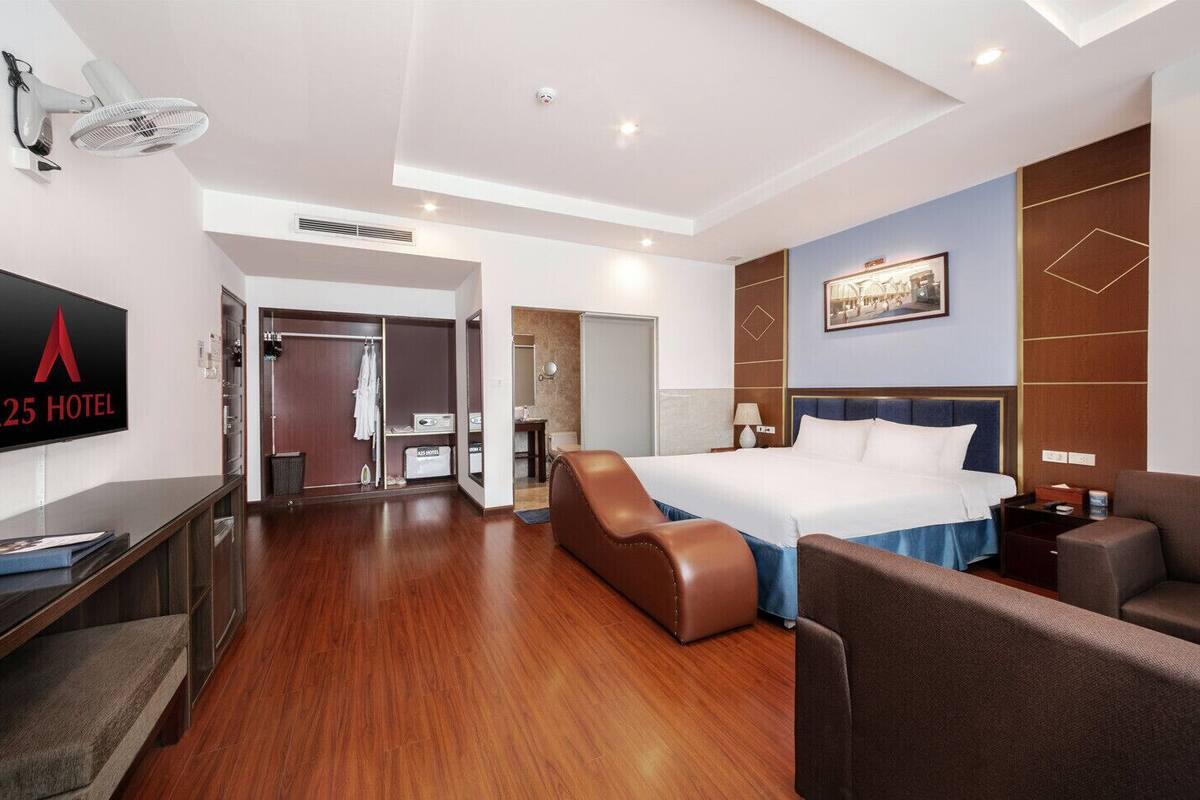 Une chambre d’hôtel comprenant un lit, un coin salon, un bureau et une télévision.
