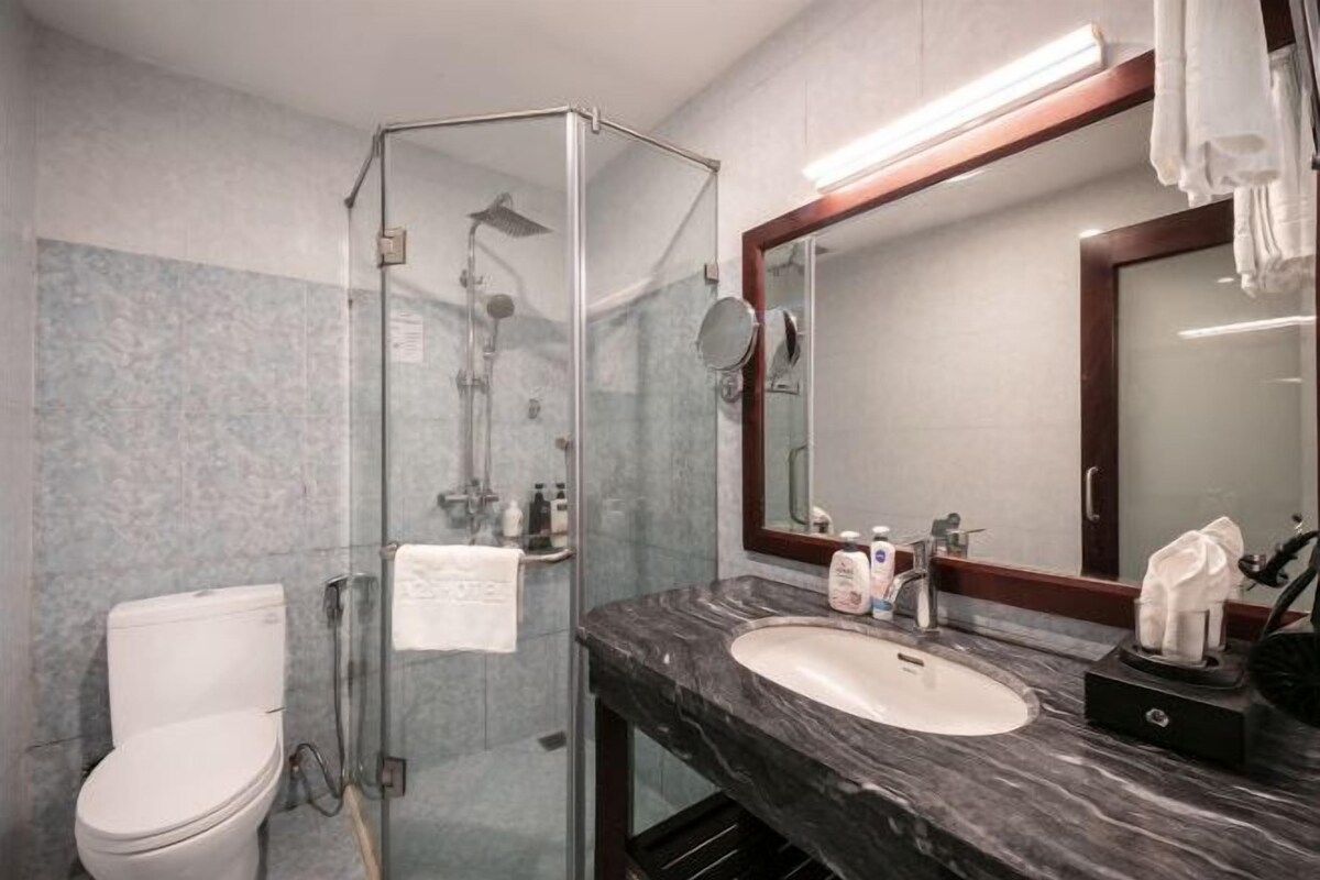 Un bagno con doccia vetrata, un water bianco, un lavabo in marmo e uno specchio grande.