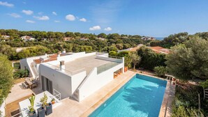 Una casa moderna con terraza en la azotea, piscina y vistas del paisaje circundante.