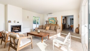 Una sala de estar con sofá, sillas, una mesita de centro, chimenea y un cuadro en la pared.