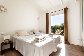 Une chambre avec deux lits, une petite table, une chaise et une vue sur la verdure.