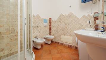 Un baño con ducha, bidé, inodoro y lavamanos.