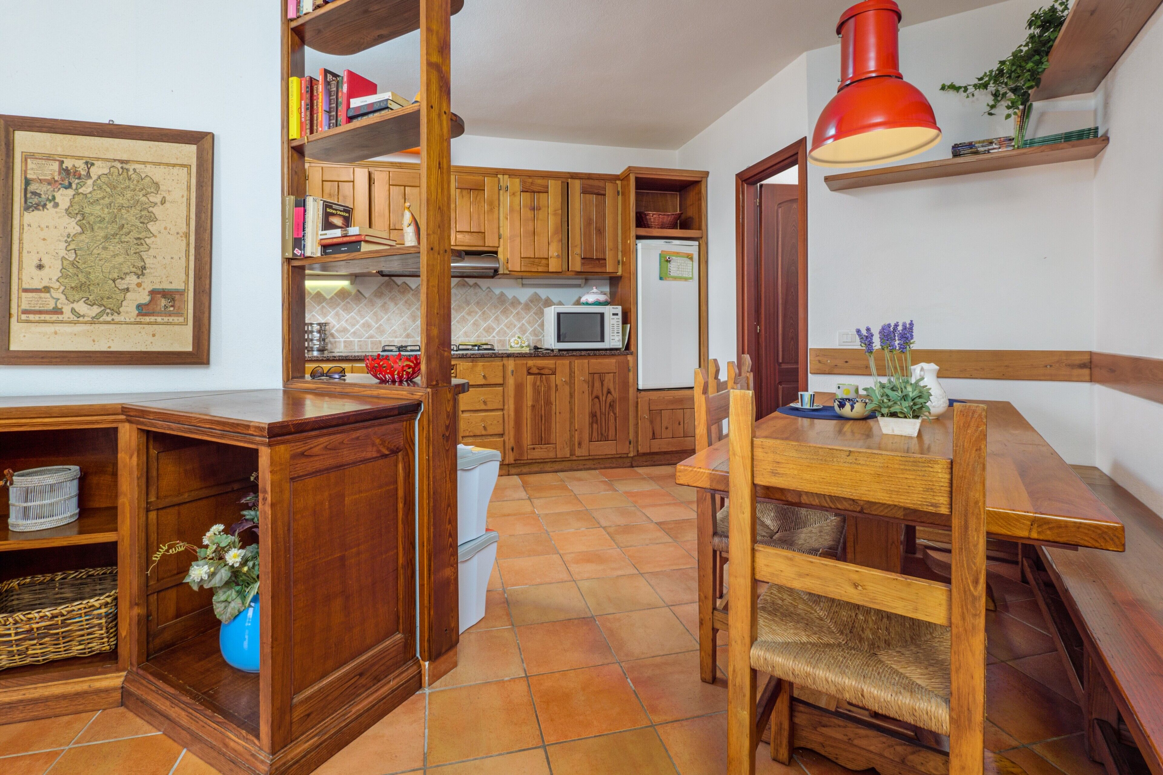 Cucina con mobili in legno, forno a microonde e tavolo da pranzo con sedie.
