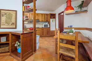Cozinha com armários de madeira, micro-ondas e mesa de jantar com cadeiras.
