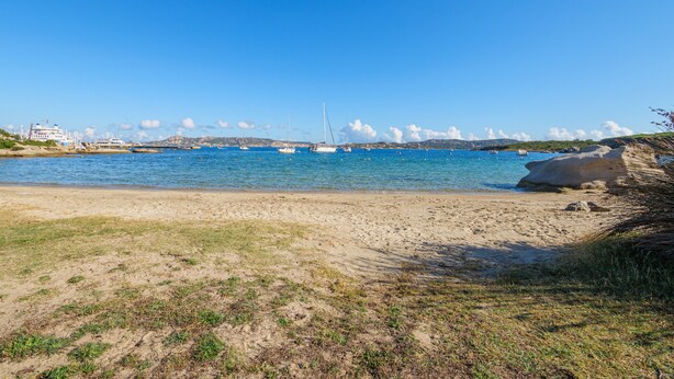 A beach with clear blue water, a sandy shore, and boats in the distance. - Apartment "Casa Erica" with Sea View, Wi-Fi & Private Terrace (Palau)