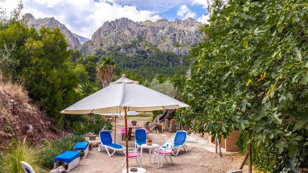 A patio with lounge chairs, a table, and an umbrella.