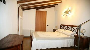 A bedroom with a wooden bed, a nightstand, a desk, and a staircase.