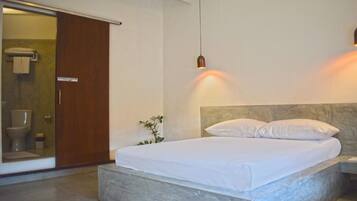 A modern bedroom with a large bed, a sliding door to the bathroom, and a pendant light.