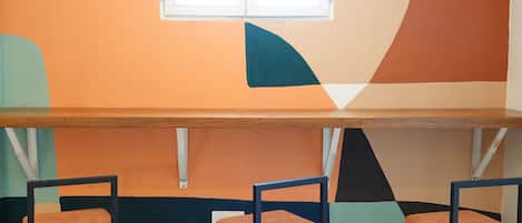 A room with a long wooden table and three chairs with orange cushions.