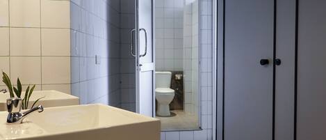Un bagno moderno con una vasca da bagno grande, un lavabo e un water visibili attraverso una porta aperta.