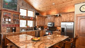 Una cocina amplia con armarios de madera, encimeras de granito, un refrigerador de acero inoxidable y una isla grande con un tazón de fruta.