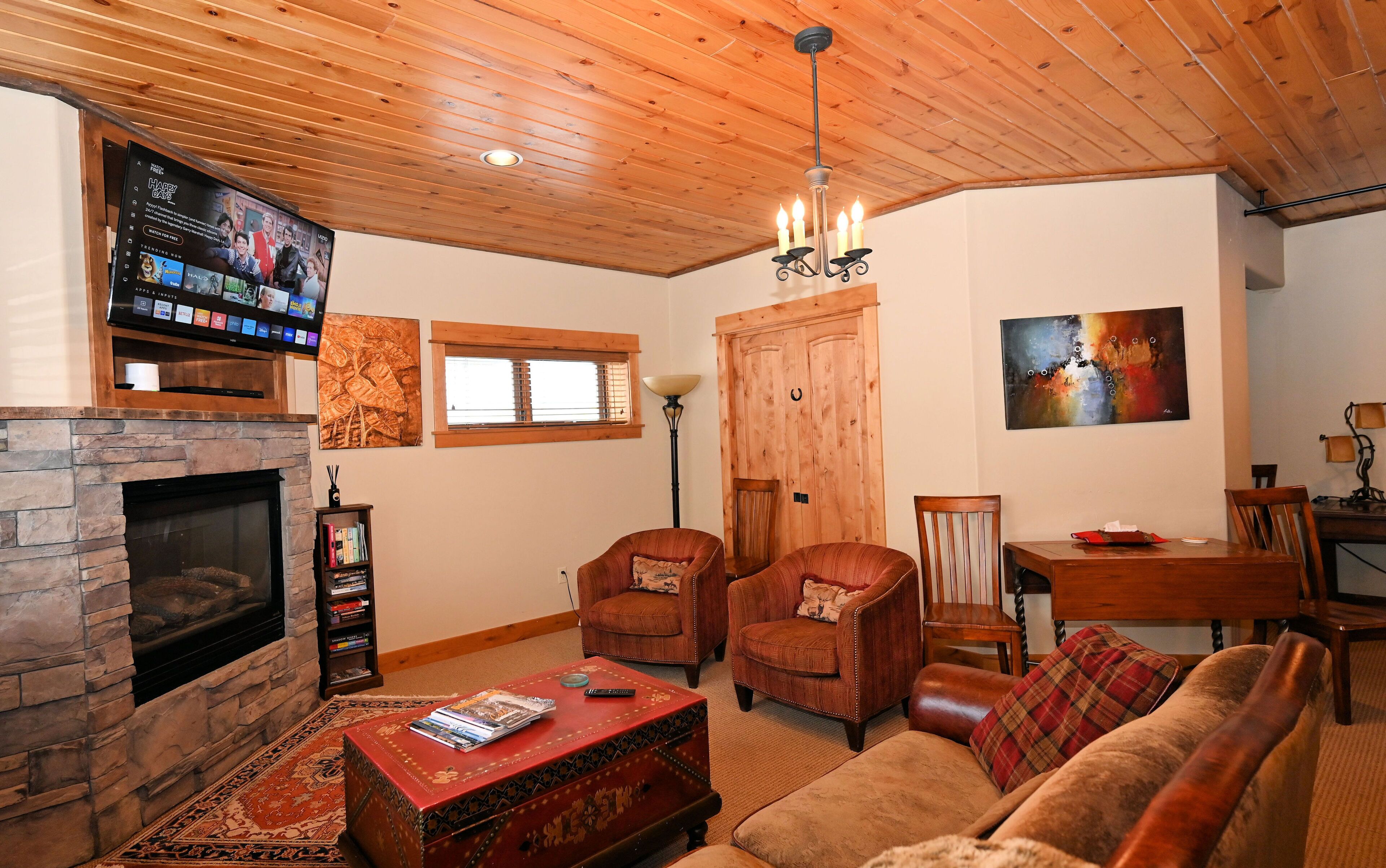 Ein gemütliches Wohnzimmer mit Kamin aus Stein, Holzboden und einem an der Wand befestigten Flachbildfernseher.