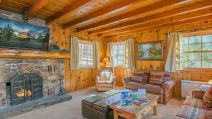 A cozy log cabin interior with a stone fireplace, wooden walls, and a comfortable seating area. - Big Bear Retreat - 2 Fireplaces, Deck, Barbecue, Fenced Yard (Big Bear Lake)