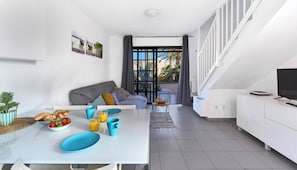 Ein stilvolles Wohnzimmer mit Essbereich, einer Couch und einem Fernseher auf einer weißen Kommode.