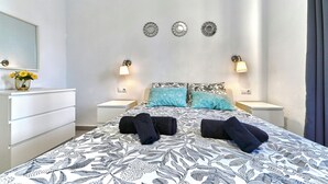 A hotel room with a bed, two bedside tables, a dresser, and a mirror.