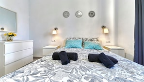 Ein Hotelzimmer mit einem Bett, zwei Nachttischen, einem Schminktisch und einem Spiegel.